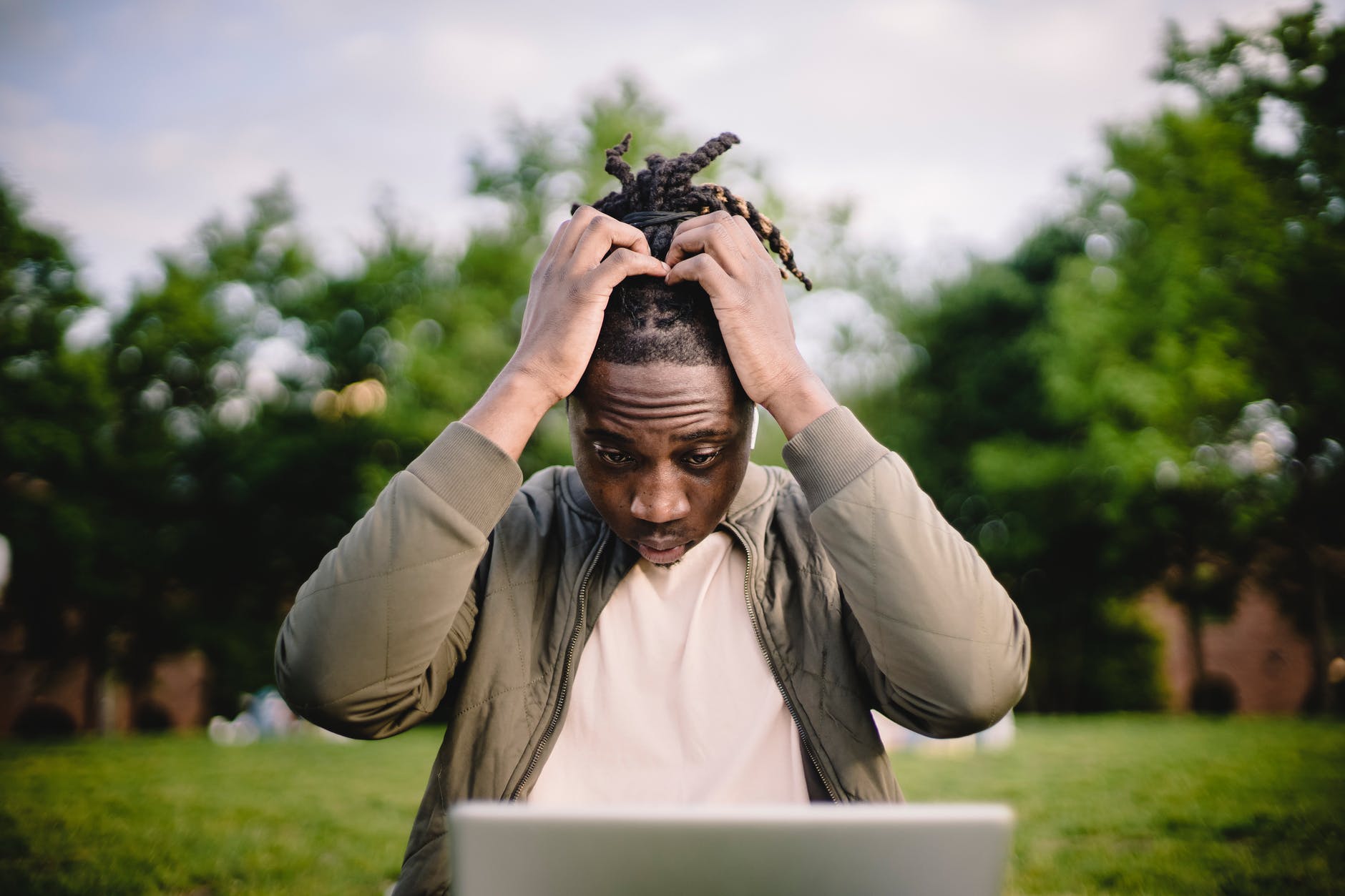 freelance mistakes of a stressed black male entrepreneur working on laptop in park